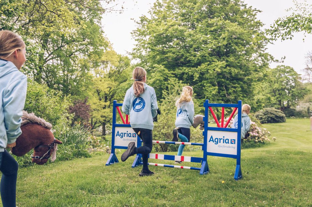 Tre barn hoppar med käpphästar.