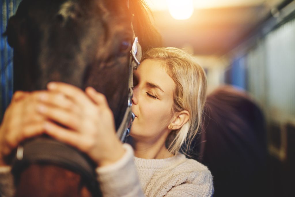 Tjej som kramar om sin häst.