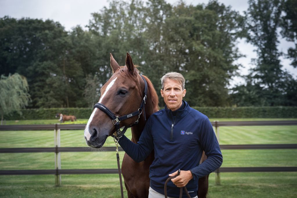 Henrik von Eckermann i Agriakläder ute i hagen med sin häst.