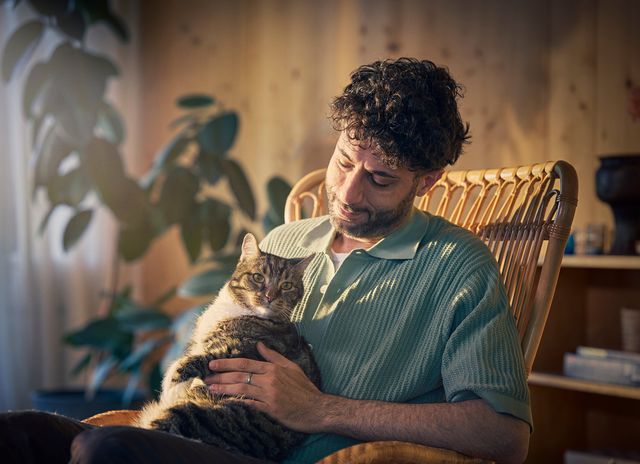 Man sitter inomhus med katt i knät