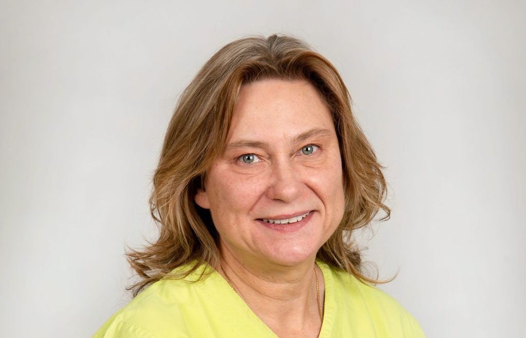 Catarina Eliasson, veterinär på Agria, i Gul veterinär tunika, tittar in i kameran med ett leende.