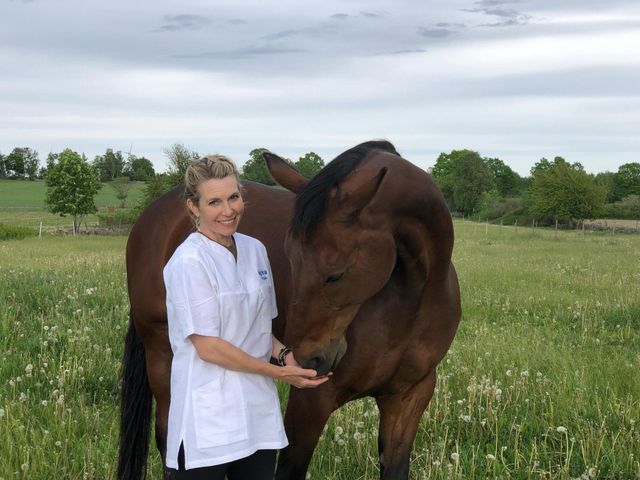 Bild på veterinär Linda Dunbäck i hage med häst.