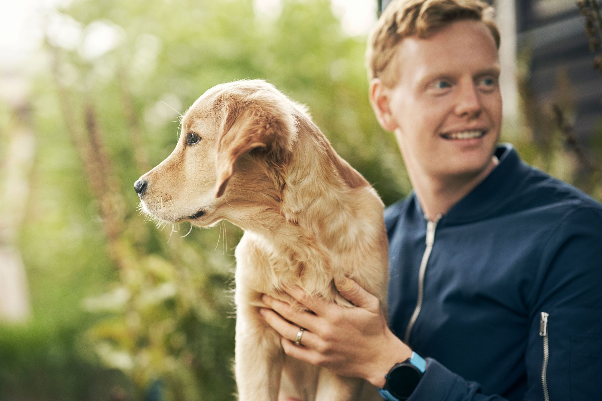 Kille klappar om hund utomhus