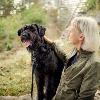 Kvinna med sin hund sitter i skogen och vilar.