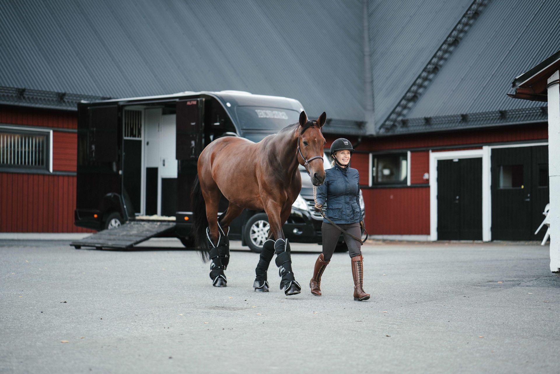 Kvinna går med häst på stallplan