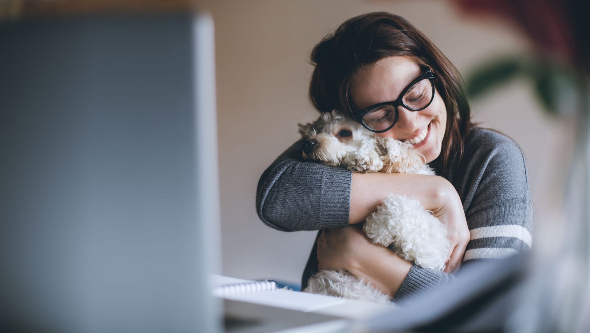 Kvinna kramar om sin hund framför datorn