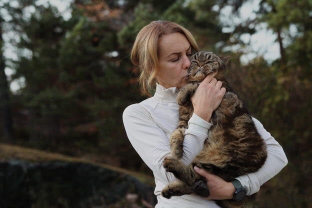 Katt blir pussar och kramad av sin matte.