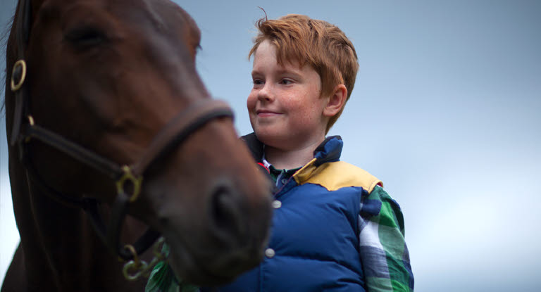 Pojke som tittar kärleksfullt på sin häst.