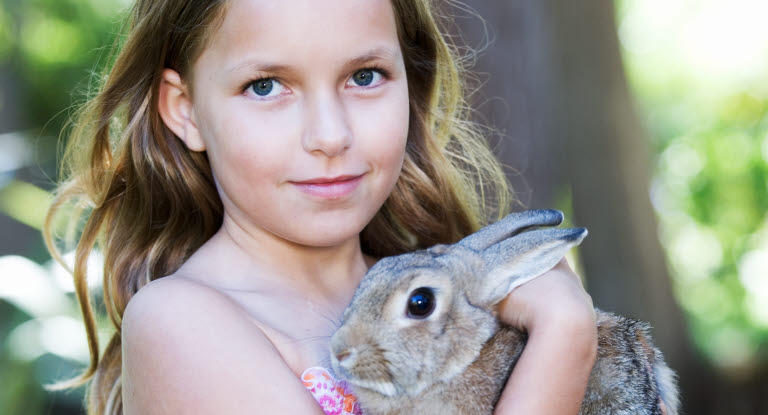 Flicka tar hand om sin kanin.