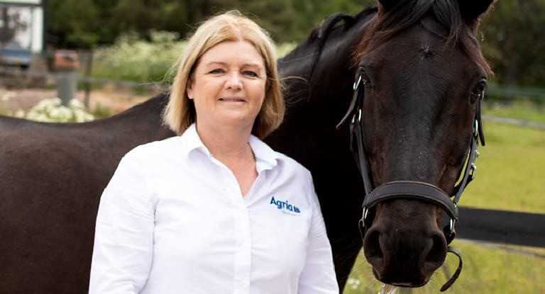 Agrias veterinär Anette Graf bredvid en brun häst.